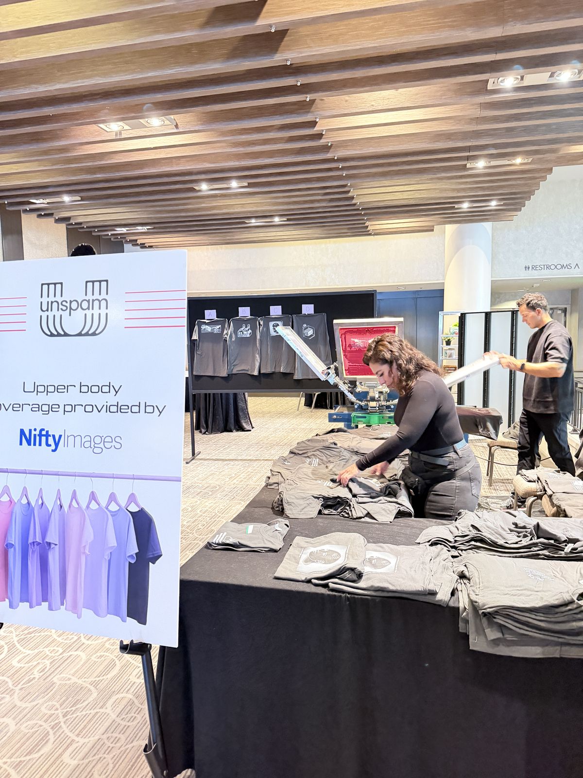 Two crew members organizing rows of garments across a long black table in a hotel foyer