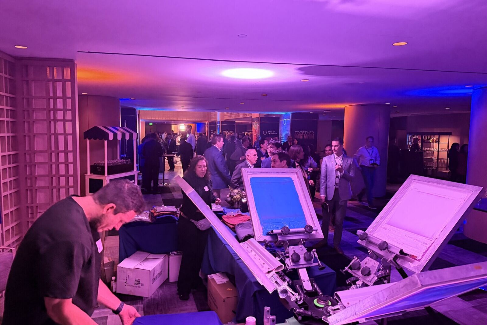 Reception hall glowing with purple uplighting while guests mingle around the customization station